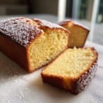 A slice of moist Almond Flour Pound Cake dusted with powdered sugar, showing its tender crumb.