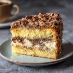 A delicious slice of Cake Mix Coffee Cake featuring layers of cake, cream cheese filling, and a nutty streusel topping.