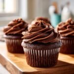 Close-up of delicious Chocolate Ganache Cupcakes with swirls of frosting on a wooden board.