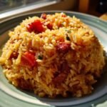 A close-up of a mound of Chorizo and Tomato Rice, showing fluffy rice mixed with chunks of chorizo and red tomato pieces.
