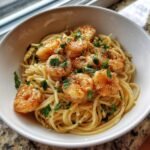 A bowl of spaghetti topped with perfectly cooked shrimp and fresh parsley, showcasing one of the 10 delicious cooked shrimp recipes.