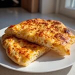 Close-up of two slices of Irresistible Easy Cottage Cheese Flatbread on a white plate, with golden-brown cheesy topping.