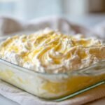 Close-up of a creamy, fluffy cream cheese gelatin dessert topped with whipped cream and lemon zest.