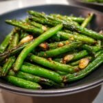 Close-up of a bowl filled with delicious garlic roasted green beans, glistening and perfectly cooked.