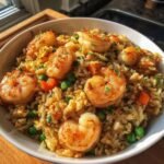 A bowl of Delicious Shrimp Fried Rice Easy Takeout Style, topped with plump, perfectly cooked shrimp and mixed with peas and carrots.