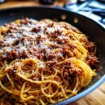 A close-up of a pan filled with Delicious Spaghetti With Homemade Meat Sauce, topped with grated Parmesan cheese.