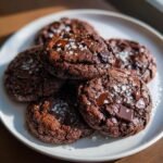A pile of double chocolate zucchini cookies with sea salt sprinkled on top.
