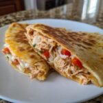 Close-up of a cheesy chicken quesadilla melt, filled with shredded chicken, peppers, and melted cheese.
