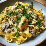 A close-up of a bowl of Flavorful Creamy Mushroom Chicken Pasta, featuring fettuccine, tender chicken pieces, mushrooms, and a rich sauce, garnished with fresh parsley.