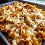 Close-up of baked Irresistible BBQ Chicken Mac and Cheese in a baking dish, with melted cheese and shredded chicken.