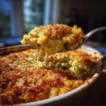 A spoonful of Irresistible Cheesy Broccoli Rice Casserole, showing melted cheese strings and a golden brown topping.
