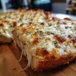 Close-up of Irresistible Cheesy Garlic Bread Pizza Toast with melted, gooey cheese and herbs.