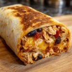 Close-up of an Irresistible Chicken Burrito, showing shredded chicken, black beans, cheese, and salsa.