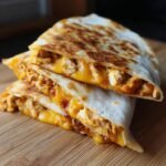 A stack of three Irresistible Chicken Quesadillas, cut in half, showcasing melted cheese and shredded chicken filling.