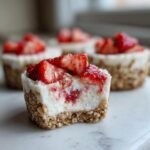 Close-up of an irresistible high protein healthy strawberry cheesecake bite with a bite taken out, showing creamy filling and strawberry chunks.