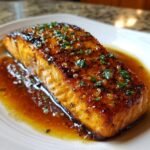 A close-up of an irresistible honey butter garlic salmon fillet, glistening with sauce and topped with fresh parsley.