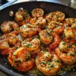 Close-up of Irresistible Roasted Garlic Butter Shrimp sizzling in a pan with garlic and herbs.