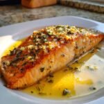 A perfectly cooked fillet of Irresistible Salmon With Garlic Lemon Butter, glistening in its sauce.