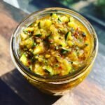 Close-up of a jar filled with Irresistible Zucchini Relish, featuring chopped zucchini, spices, and chili flakes.