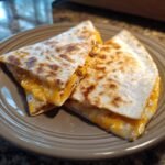 Two golden-brown Keto Cheeseburger Quesadillas sliced in half, revealing gooey melted cheese and seasoned ground beef filling.