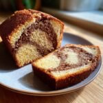 A slice of moist Mile High Sock It To Me Pound Cake with a beautiful cinnamon swirl on a plate.