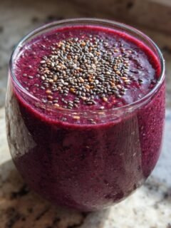 A glass of vibrant purple Nutritious Dinner Replacement Smoothie topped with chia seeds.