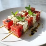 Close-up of refreshing feta and watermelon skewers drizzled with balsamic glaze and topped with mint.