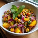 A vibrant bowl of Refreshing Nectarine Salad with Chickpeas, featuring sliced nectarines, chickpeas, red onion, and fresh mint.