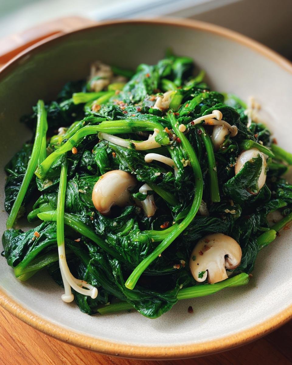 A close-up shot of sautéed spinach and enoki mushrooms in a bowl, seasoned with chili flakes.