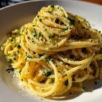 A close-up of perfectly twirled Garlic Butter Pasta topped with grated cheese and fresh green parsley.