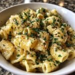 A close-up of a bowl filled with Irresistible Easy Garlic Parmesan Pasta, garnished with fresh parsley and red pepper flakes.