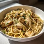 A bowl of Irresistible Garlic Parmesan Healthy Chicken Pasta topped with fresh parsley.