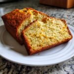 Two slices of Irresistible Mouthwatering Lemon Zucchini Bread on a white plate, showing the moist crumb and flecks of zucchini.