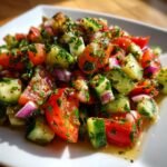 A close-up view of a Refreshing Cucumber Tomato Salad Recipe Bliss, featuring chopped tomatoes, cucumbers, red onion, and fresh herbs in a light dressing.
