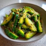 Close-up of a bowl filled with refreshing Tik Tok Korean cucumber salad, glistening with a savory dressing and sprinkled with sesame seeds.