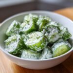 Close-up of a white bowl filled with refreshing tzatziki cucumber salad, garnished with fresh dill.
