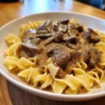 Close-up of a white bowl filled with Amazing Beef Stroganoff served over wide egg noodles.