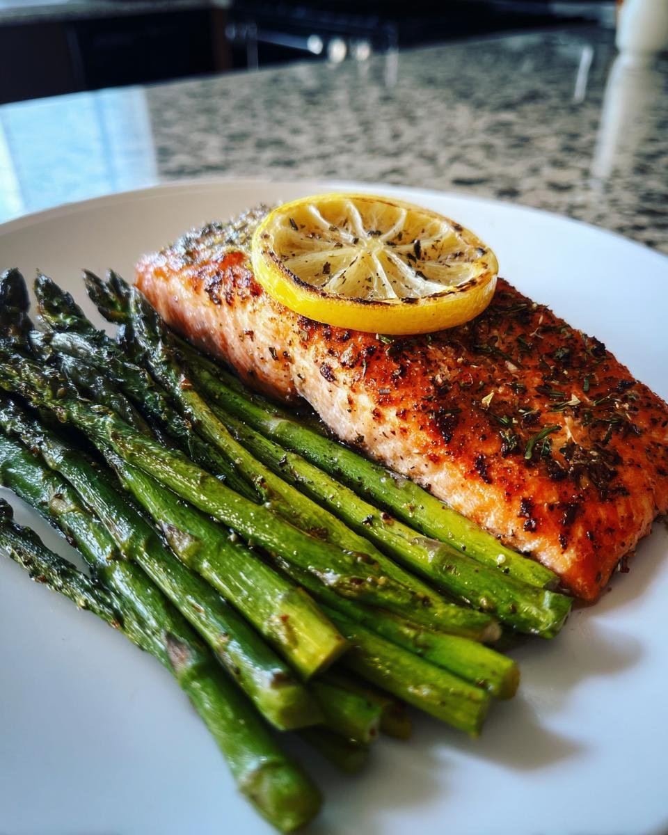 A perfectly cooked fillet of Baked Sockeye Salmon With Asparagus, topped with a lemon slice.