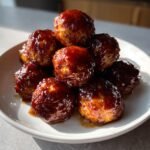 A stack of glistening Brown Sugar Glazed Turkey Meatballs piled high on a white plate.