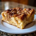 A close-up of a moist slice of Cinnamon Apple French Toast Casserole with a caramelized, cinnamon-sugar topping.