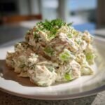 A close-up of a generous scoop of Creamy Dill Chicken Salad with visible celery chunks and topped with fresh dill.
