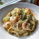 A close-up of rich Creamy Shrimp Fettuccine tossed in white sauce and garnished with fresh parsley.