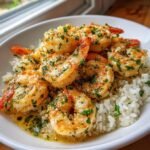 Close-up of juicy Garlic Butter Shrimp And Rice topped with fresh parsley in a white bowl.