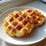 Two golden brown Easy Chaffles resting on a white plate, perfectly cooked with deep waffle indentations.
