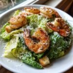 Close-up of a fresh Grilled Shrimp Caesar Salad topped with grated Parmesan cheese and croutons.