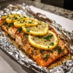 Close-up of a cooked Lemon Pepper Salmon Foil Packets topped with lemon slices and fresh parsley.