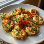 Close-up of perfectly cooked Garlic Shrimp coated in butter sauce and fresh chopped parsley on a white plate.