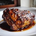 Close-up of a perfectly cooked piece of Saucy Chicken coated in a thick, glossy brown glaze, resting in its sauce.