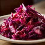 Close-up of a mound of bright, glossy Red Cabbage Slaw served on a white plate.