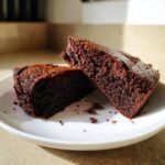 Two rich, dark slices of moist Brownie Bread displayed on a white plate.